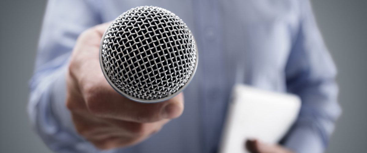 Hand holding a microphone conducting a business interview or press conference